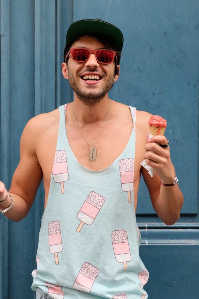 Happy man in Paris enjoying ice cream against a blue door. Fashionable and fun summer vibe.